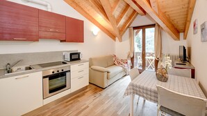 Eine kleine Küche mit Mikrowelle, Backofen und Spüle, ein beiges Sofa und ein Tisch mit einem Korb.