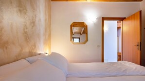 Une chambre à coucher avec un grand lit, un plafond en bois, un miroir et une porte donnant sur une autre pièce.