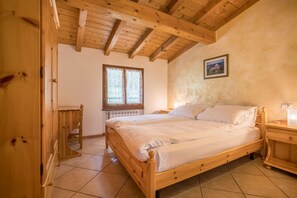 A wooden bed in a room with a sloped ceiling and a window.
