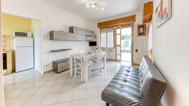 A modern kitchen with a dining area, a sofa, and a TV. - Holiday Apartment "Baia Del Mare" with 2 Private Terraces, Private Garden & A/C (Lido Marini)
