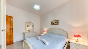 A bedroom with a bed, nightstands, a dresser, a mirror, and a door. - Holiday Apartment "Baia Del Mare" with 2 Private Terraces, Private Garden & A/C (Lido Marini)