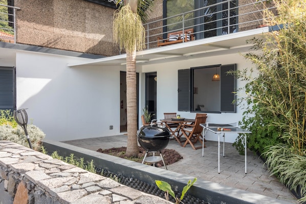 Un patio exterior moderno con una parrilla, asientos y vistas del interior del edificio.
