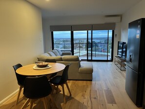 Enjoy a compact living space with a dining area and seating area, featuring a round table, comfortable sofa, and flat-screen TV.
