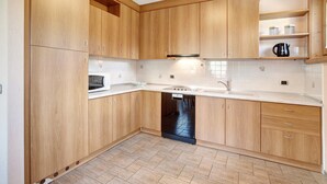Una cocina con armarios de madera, lavavajillas, microondas y cafetera.