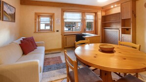 Quarto aconchegante com mesa de jantar de madeira, um sofá e janela com vista.