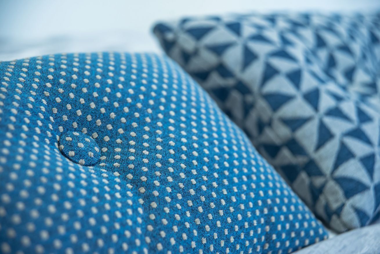 Un gros plan d’un coussin bleu orné d’un motif à pois blancs.