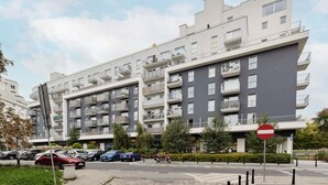 Un edificio residencial de varios pisos con balcones, una señal de prohibido estacionar y automóviles estacionados.