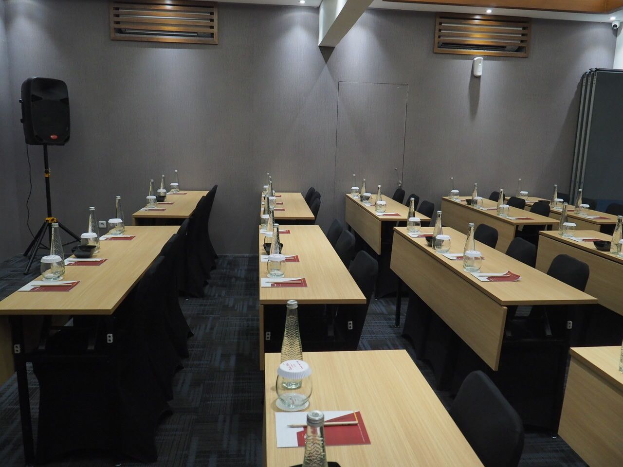 A conference room with multiple tables, chairs, and a speaker on a tripod.