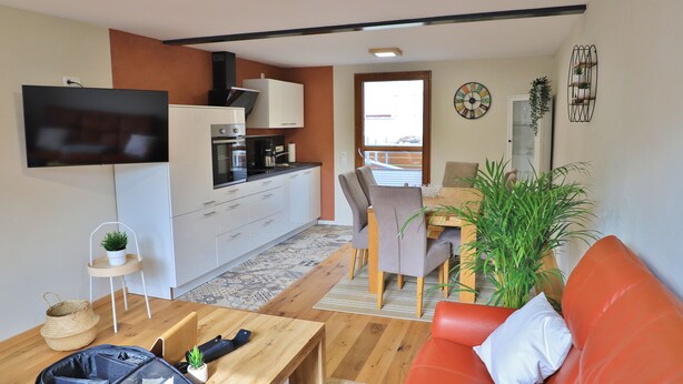 A compact living space with a kitchenette, a dining area, and a seating area with a sofa and chairs.