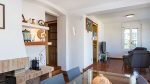 Ein modernes Wohnzimmer mit einem Glastisch, bequemen Sitzgelegenheiten, einem Kamin und einem Fernseher im Hintergrund.