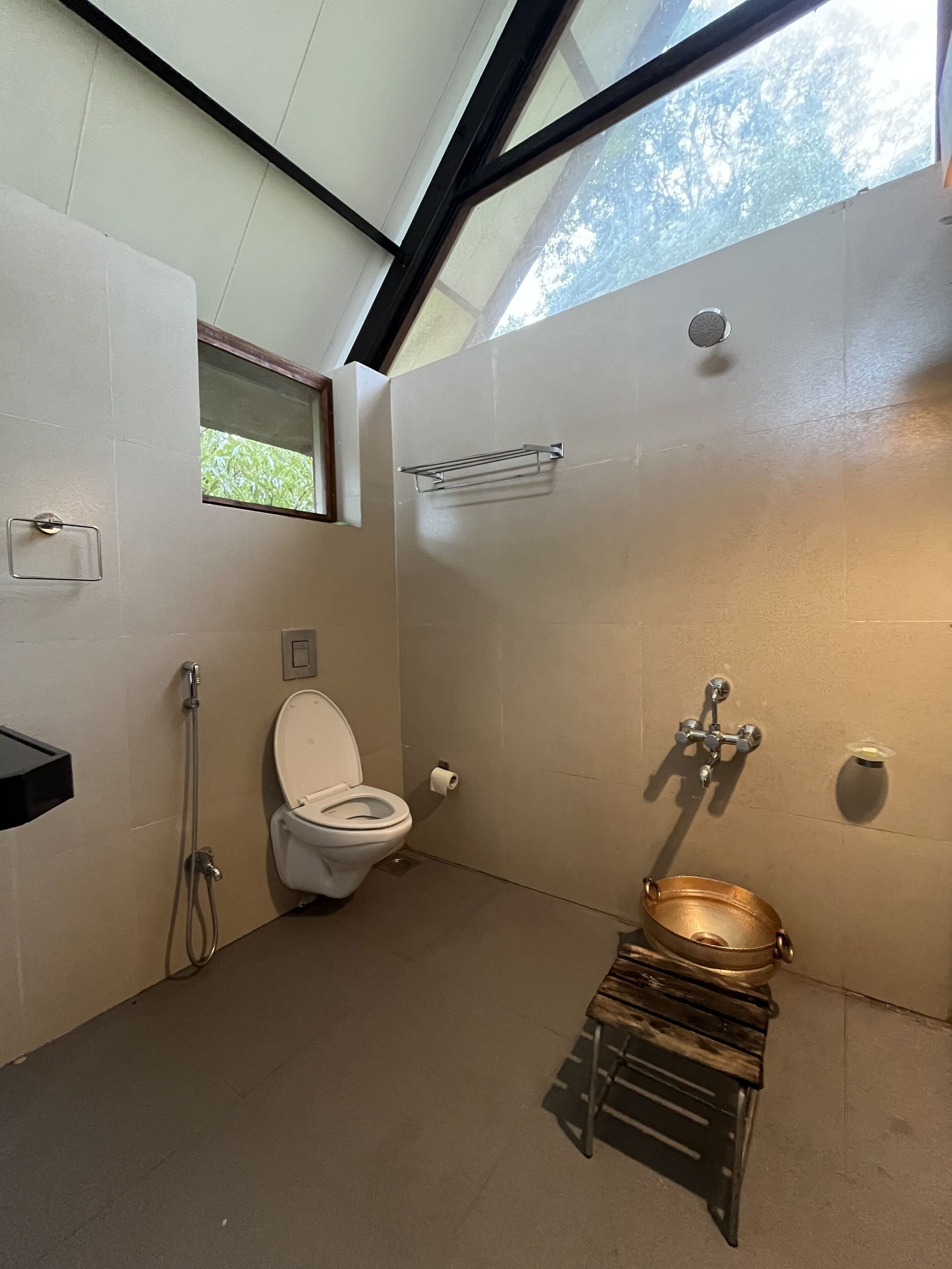 Un bagno moderno con finestra a lucernario, un water, una doccia e una panca in legno.