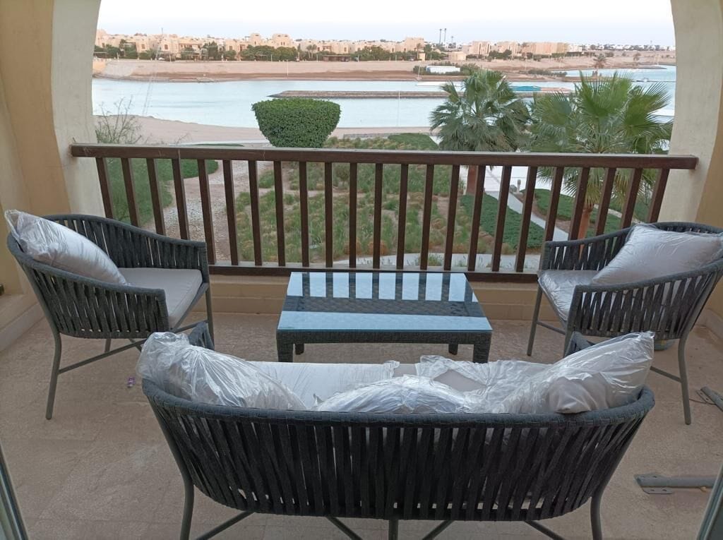 Un balcon avec des meubles en osier, une vue sur la plage et des palmiers.
