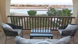 A balcony with wicker furniture, a view of the beach, and palm trees. - El-Gouna, Water Side, 3 room apartment, Sunny, Modern with pool, WaterSki view (El-Gouna)