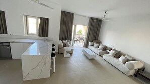 A modern living room with a marble island, a sofa set, and a dining area with a kitchen in the background. - El-Gouna, Water Side, 3 room apartment, Sunny, Modern with pool, WaterSki view (El-Gouna)