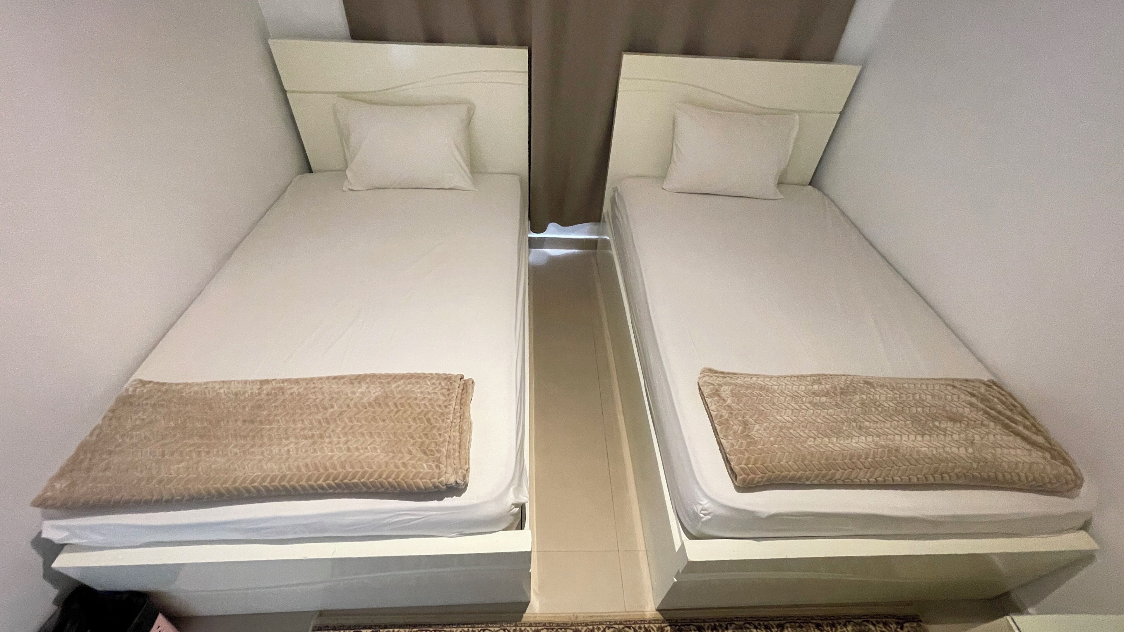 Une chambre double avec deux lits simples, chacun étant équipé d’un oreiller et d’une couverture.