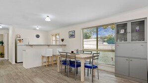 Een moderne keuken met een eethoek, met een houten tafel, stoelen en een koelkast.