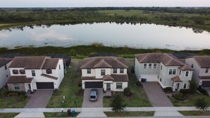 A residential area with houses, a pond, and solar panels. - Beautiful 4 Bedroom Home With Pool Overlooking Lake Views (Haines city)
