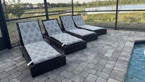 A poolside area with three lounge chairs and a pool. - Beautiful 4 Bedroom Home With Pool Overlooking Lake Views (Haines city)