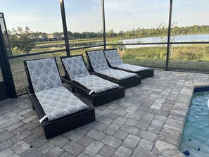 Un área junto a la piscina con tres sillas reclinables.