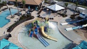 A water park with a large pool, a water slide, and a play structure.