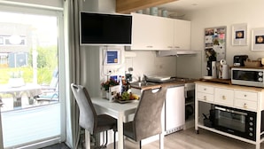 Une cuisine moderne avec des meubles blancs, un plafond en bois et un coin repas équipé de deux chaises.