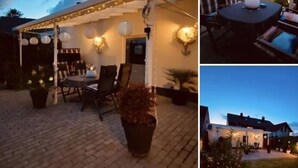 Un espace extérieur abrité, agrémenté de guirlandes lumineuses, d’une table, de chaises et de plantes en pot.
