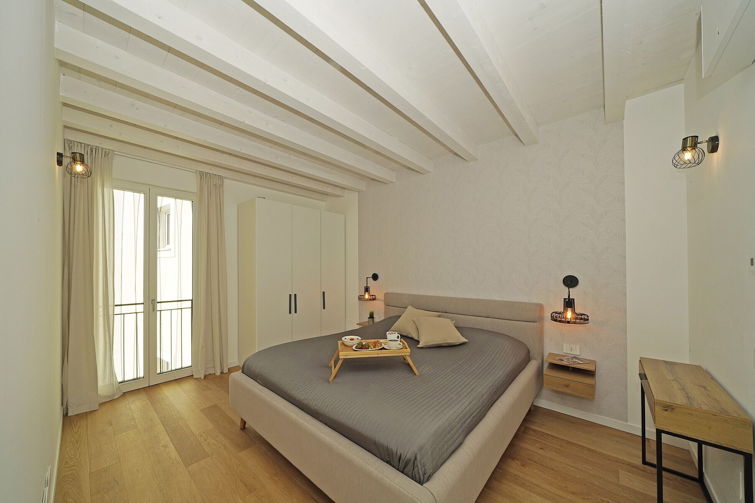 A bedroom with a bed, bedside tables, a wooden nightstand, and a small table.