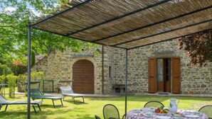 A stone building with a covered patio area, outdoor seating, and a table set for dining.