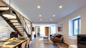 Un espace de vie moderne comprenant un coin repas, un escalier, un canapé et un téléviseur.