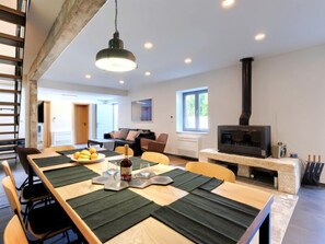 Un salon moderne comprenant un coin repas, une cheminée et une grande fenêtre.