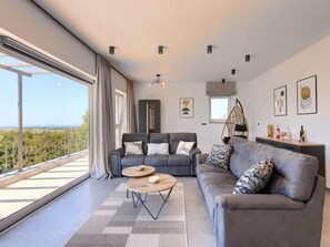 Un salon moderne avec un canapé gris, une table basse ronde et un fauteuil suspendu.