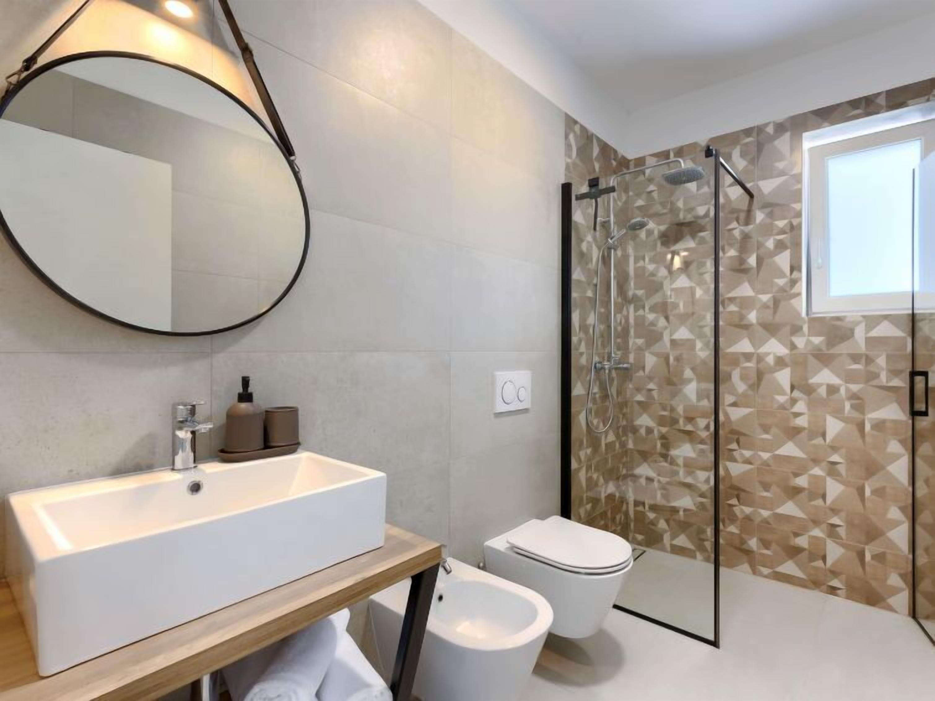 A modern bathroom with a large rectangular sink, a toilet, and a glass-enclosed shower.