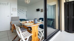 Un comedor moderno con una mesa de madera y sillas blancas, un ventanal con vistas, y una lámpara en el techo.