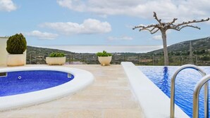 Una piscina sul tetto con vista chiara sul paesaggio circostante, tra cui colline e un corpo d'acqua in lontananza.