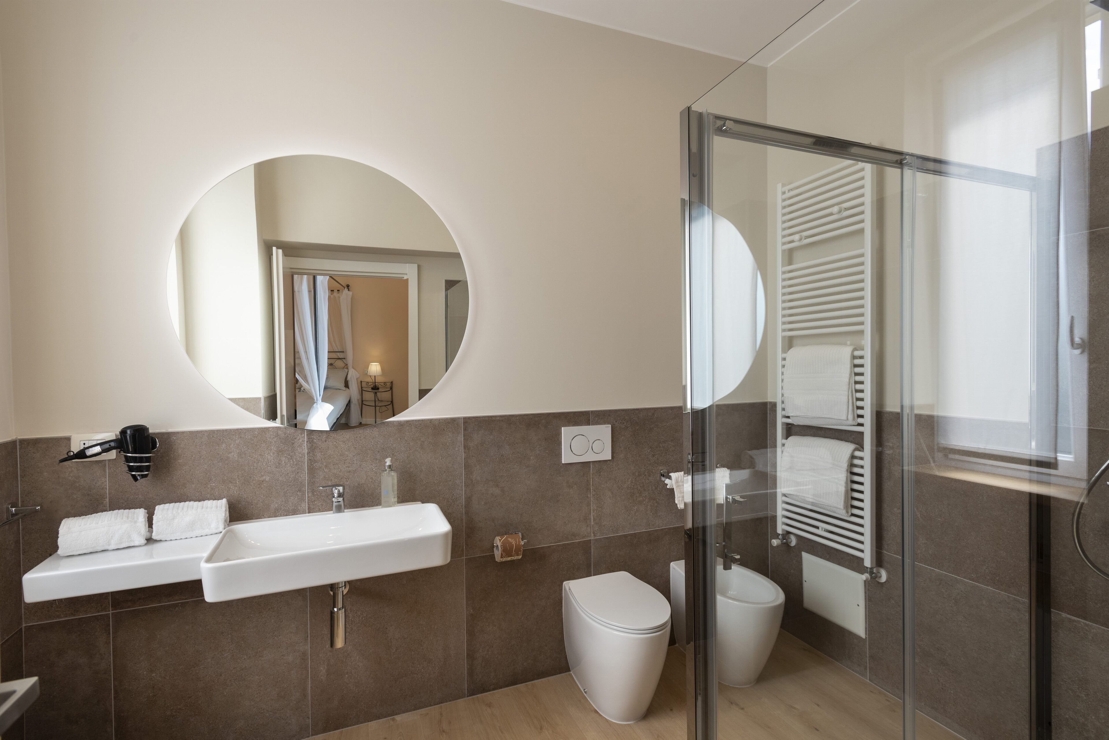 A modern bathroom with a large mirror, a sink, a toilet, and a shower area.