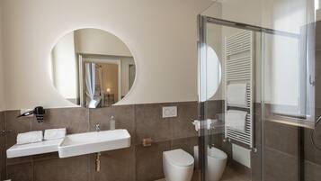 A modern bathroom with a large mirror, a sink, a toilet, and a shower area.