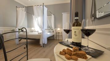 Un dormitorio con una cama, una mesita de noche con una botella de vino y copas, y un plato de churros.