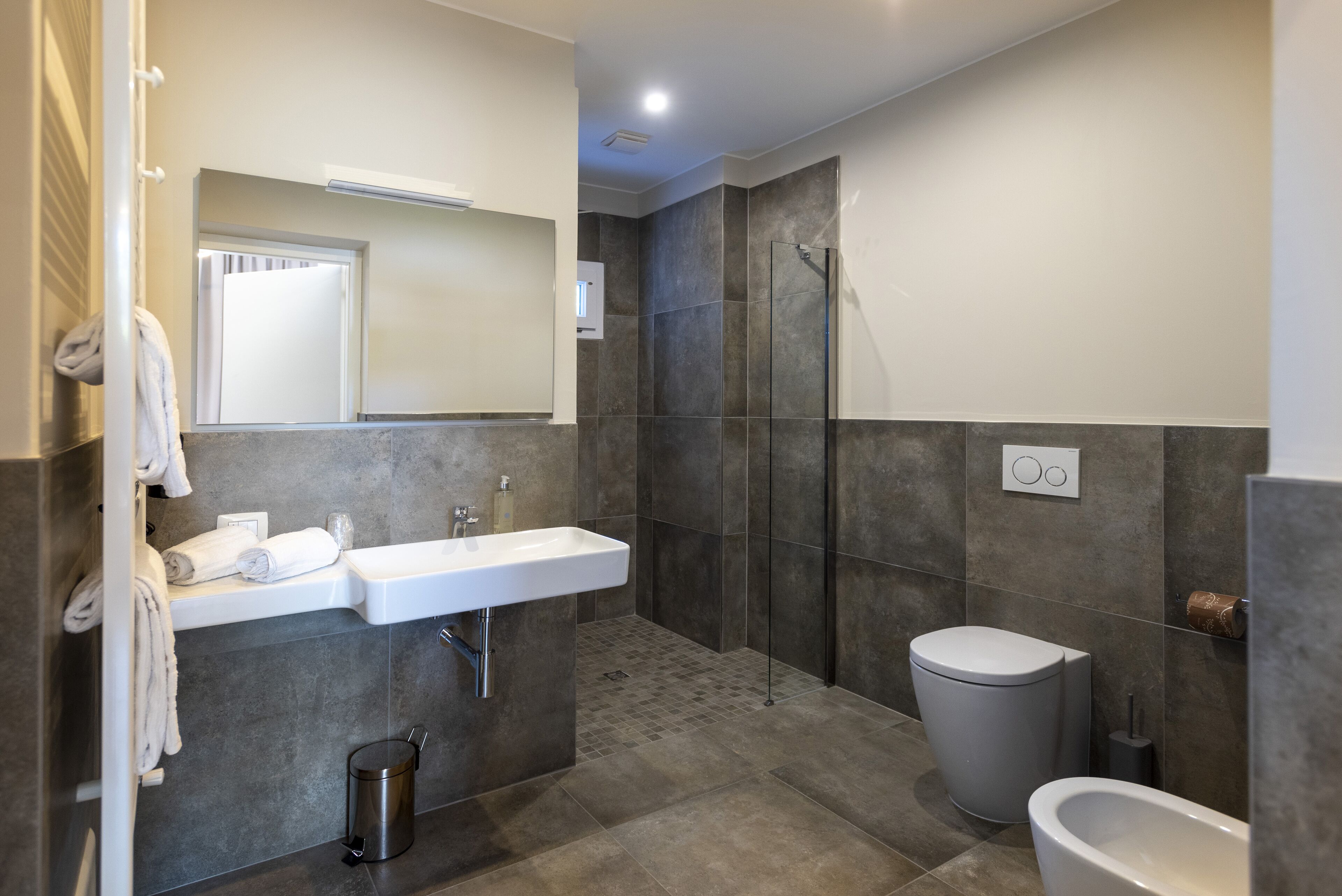 Une salle de bain moderne avec une douche à parois de verre, un lavabo blanc et des toilettes.