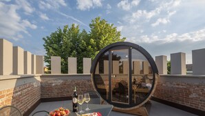 A rooftop terrace with a round glass enclosure, a table with a bottle of wine, glasses, and a plate of food. - Villa Bernasconi - camere e ristorante - (Narzole)