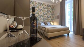 Een hotelkamer met een bed, een eettafel en twee wijnglazen op een dienblad.