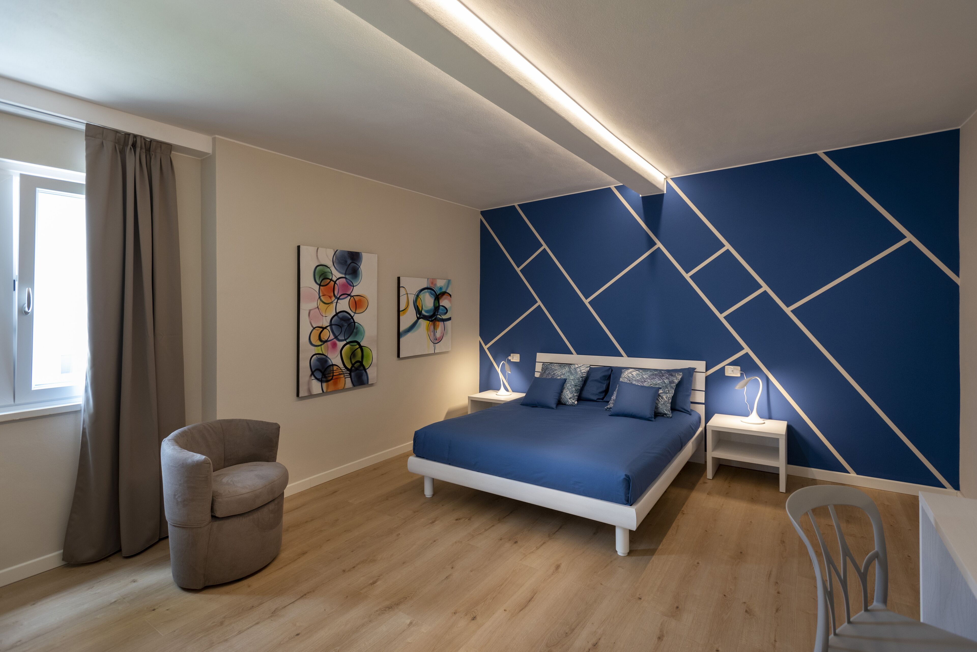 Ein modernes Schlafzimmer mit einem Bett, einem Sessel und Kunstwerken an der Wand.