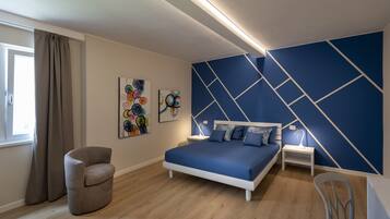 Ein modernes Schlafzimmer mit einem Bett, einem Sessel und Kunstwerken an der Wand.