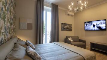 Une chambre moderne avec un grand lit, une télévision, un fauteuil et une fenêtre avec des rideaux.
