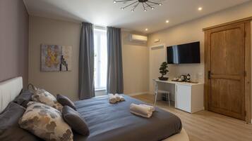Een moderne slaapkamer met een groot bed, een bureau, een televisie en een kledingkast.