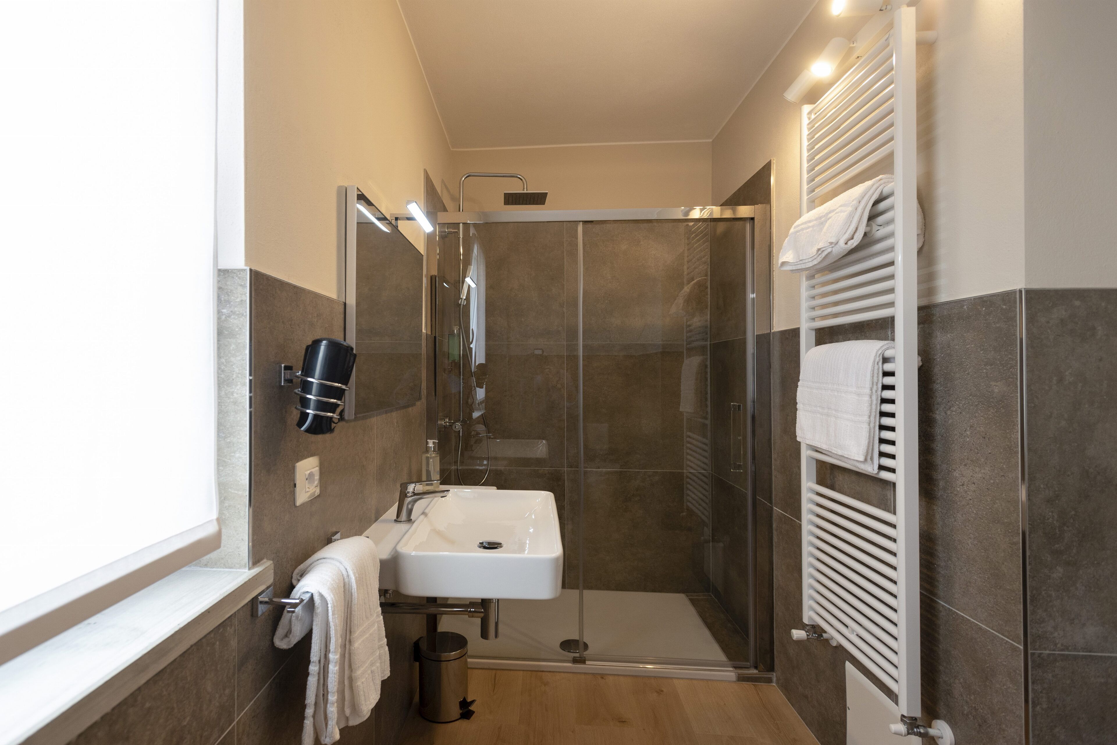 A modern bathroom with a glass-enclosed shower, a white sink, and a towel rack.