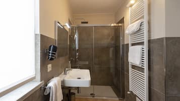 Une salle de bain moderne avec une douche à parois de verre, un lavabo blanc et un porte-serviettes.