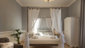 A bedroom with a four-poster bed, a nightstand, a potted plant, a wardrobe, and a chair. - Villa Bernasconi - camere e ristorante - (Narzole)