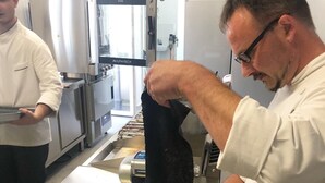 A kitchen with stainless steel appliances, a chef preparing food, and a rolling pin on the counter. - Villa Bernasconi - camere e ristorante - (Narzole)