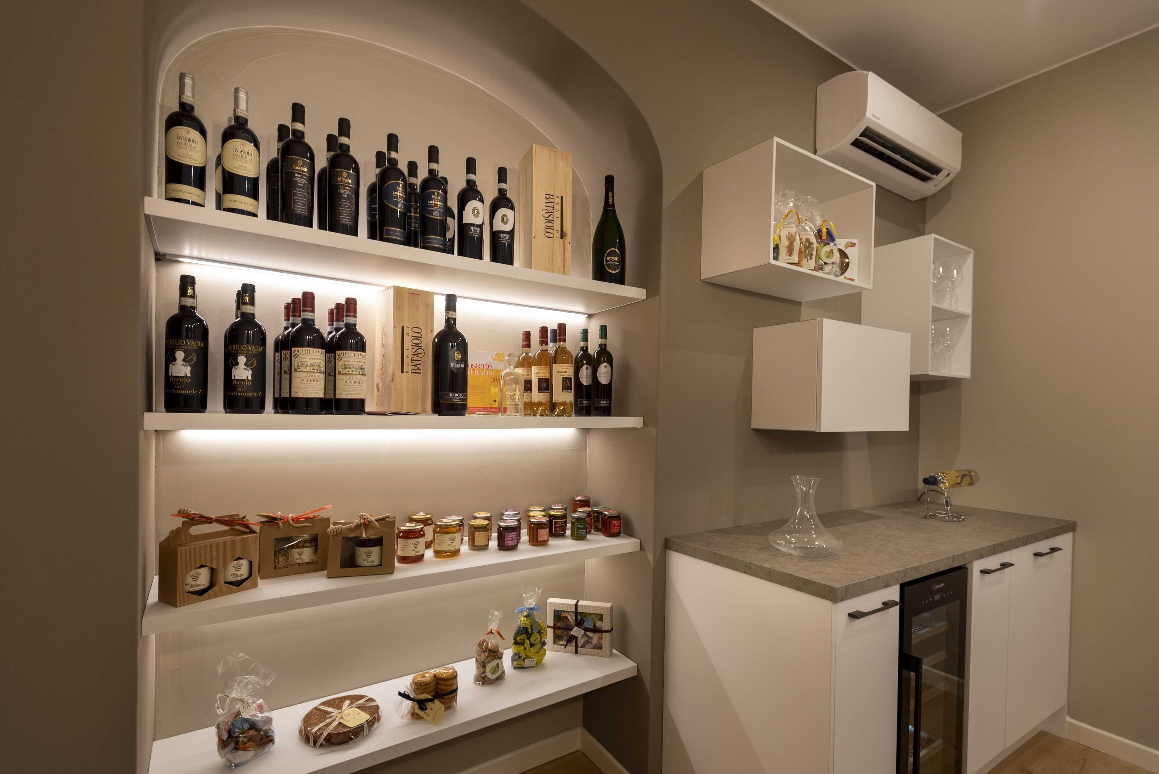 A kitchen with white cabinetry, a built-in oven, and a wine rack with various bottles.
