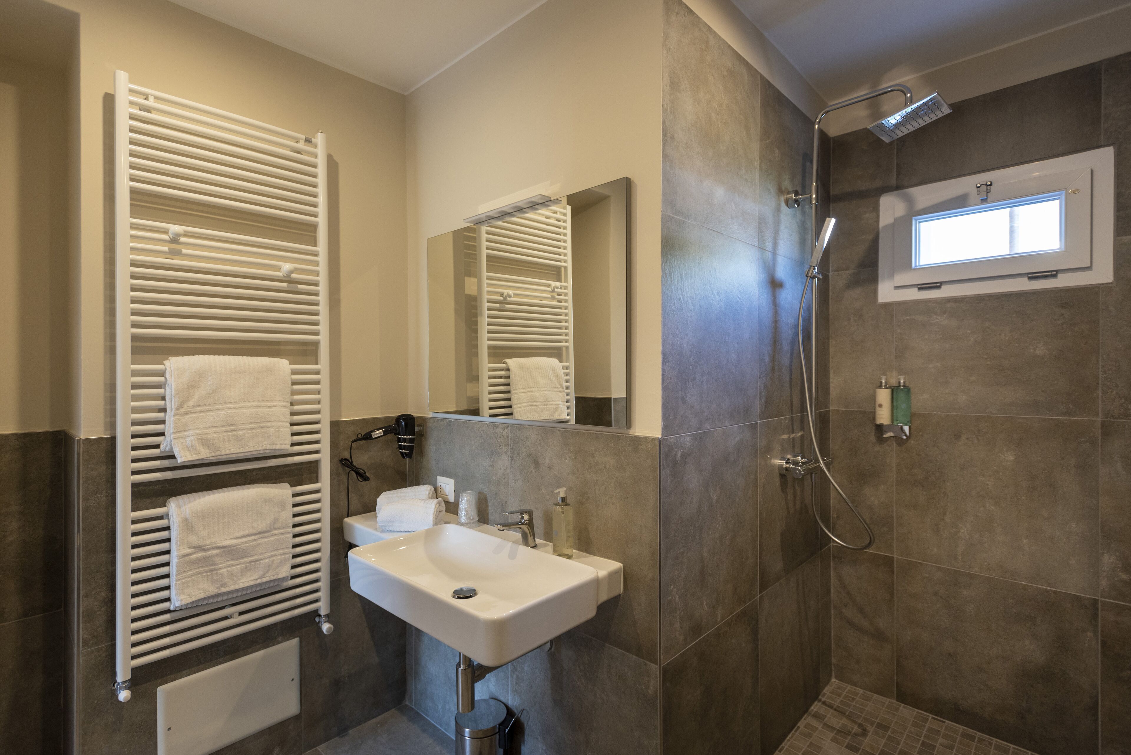 A modern bathroom with a built-in towel rack, a sink, a mirror, and a shower area.